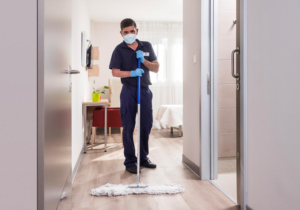 Un limpiador del centro pasando la mopa en una de las habitaciones de la residencia